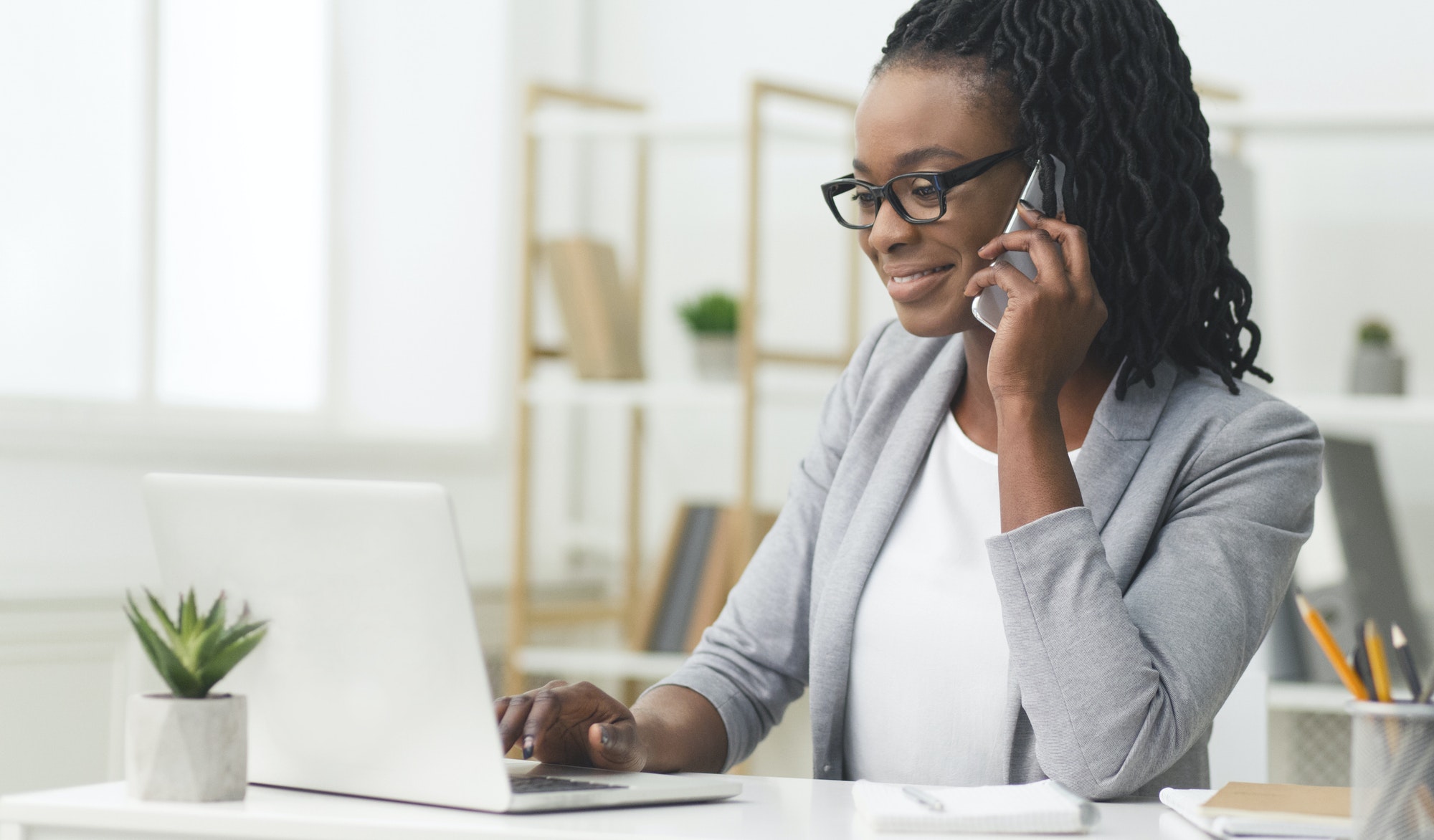 Smiling Office Girl Talking On Cellphone Using Laptop At Work